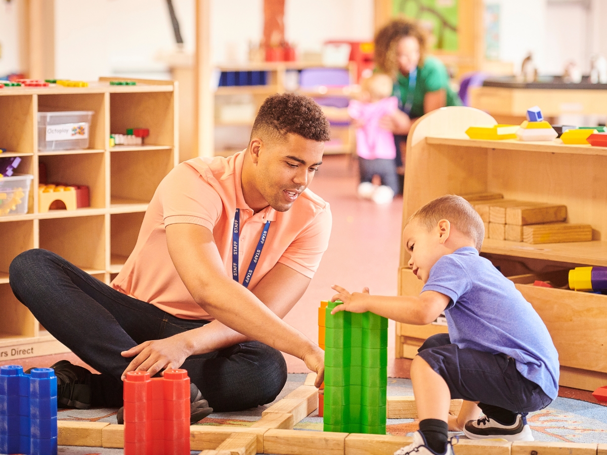 Male nursery teacher in class with a child - Texas View