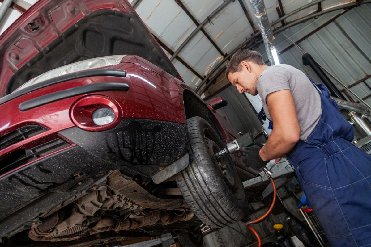 A mechanic is maintaining wheels on a vehicle in auto garage with pneumatic tool - Texas View