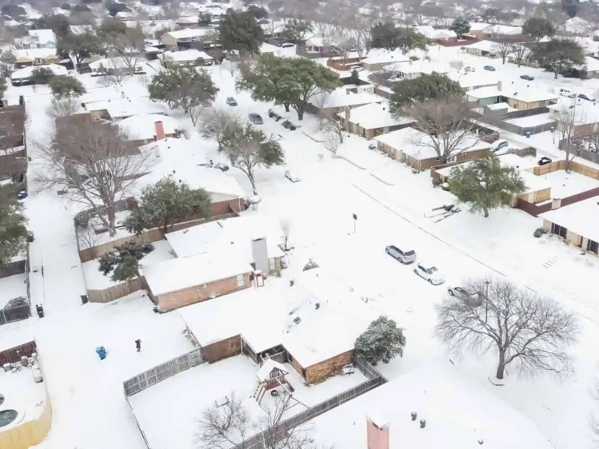 Aerial view heavy snow covered residential houses roofs and cars at neighborhood street near Dallas Texas USA. Subdivision suburban detached homes with large backyard after blizzard storm. - Texas View