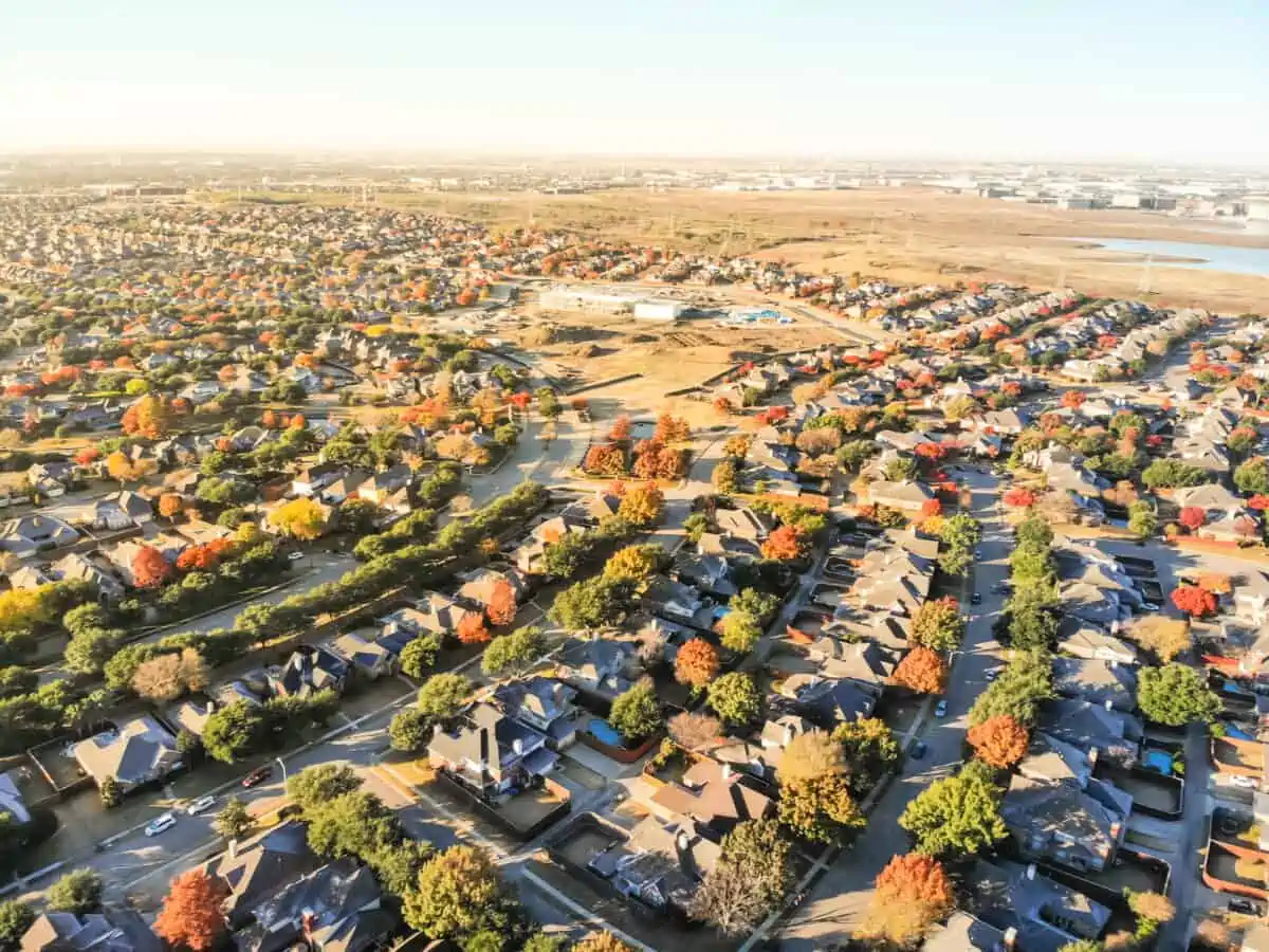 Aerial view suburban sprawl row of single family detached house on large expanses of land Dallas Texas. North Lake warehouses from industrial zone in distance. Urban areas of housing fall landscape. - Texas View