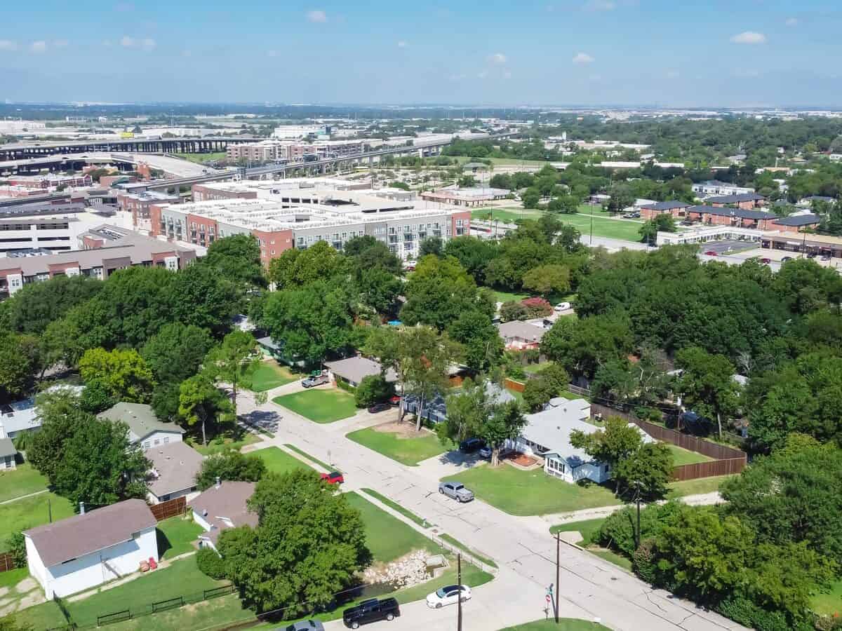 Aerial view residential neighborhood with detached family houses next to apartment buildings near historic downtown Carrollton Square Texas. Elevated highway and light rail road in background. - Texas View