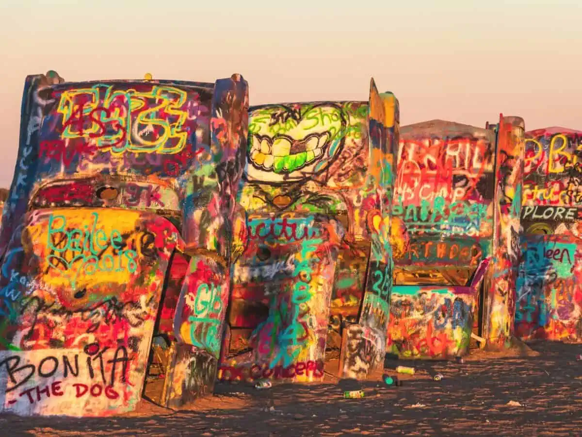 Cars in the dirt painted with Graffiti at Cadillac Ranch - Texas News, Places, Food, Recreation, and Life.
