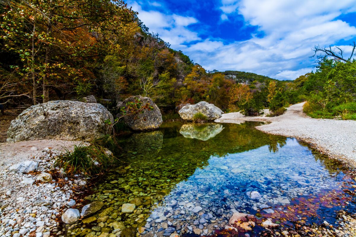 A Picturesque Scene Bursting with Beautiful Fall Foliage and Large Granite Boulders on a Tranquil Babbling Brook at Lost Maples State Park in Texas. - Texas View