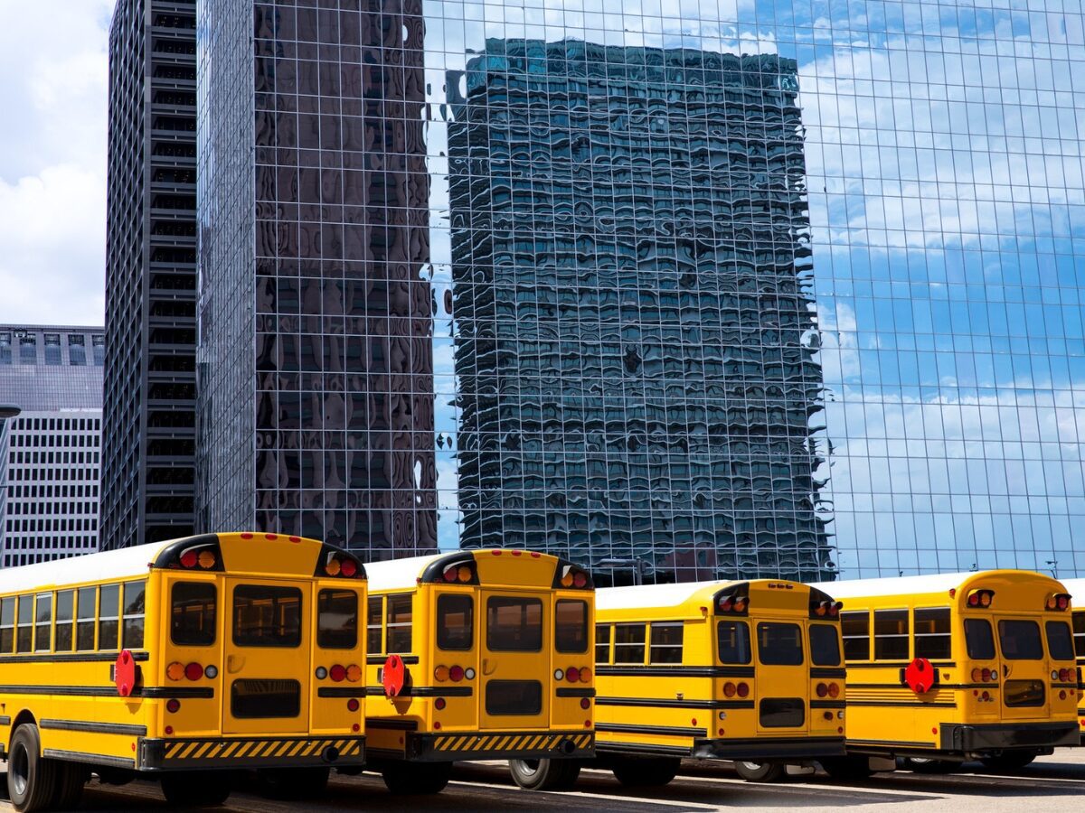 American school buses rear view in a row at Houston city skyline. - Texas View
