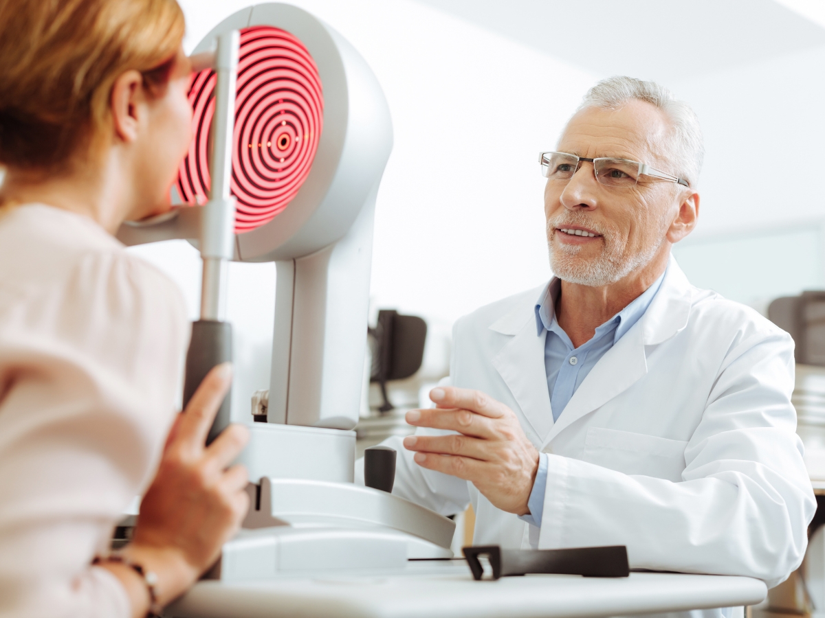 Eye therapist in glasses smiling while talking to patient - Texas View