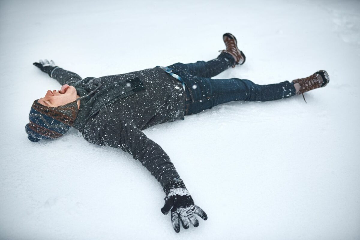 A young man lying in the snow making a snow angel - Texas View