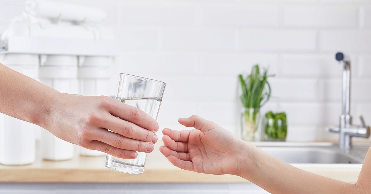 Female Hand giving a glass of clean water. Purified water and healthy life concept - Texas View
