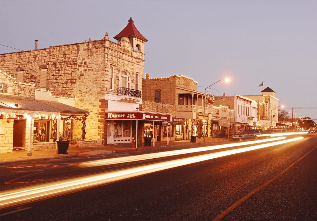 Downtown Fredericksburg. 100 block of E. Main Street, looking south towards cross street of Llano. 2-story with red tower limestone building in foreground is the Old Fredericksburg Bank designed by Alfred Giles in 1889.THC Old Fredericksburg Bank