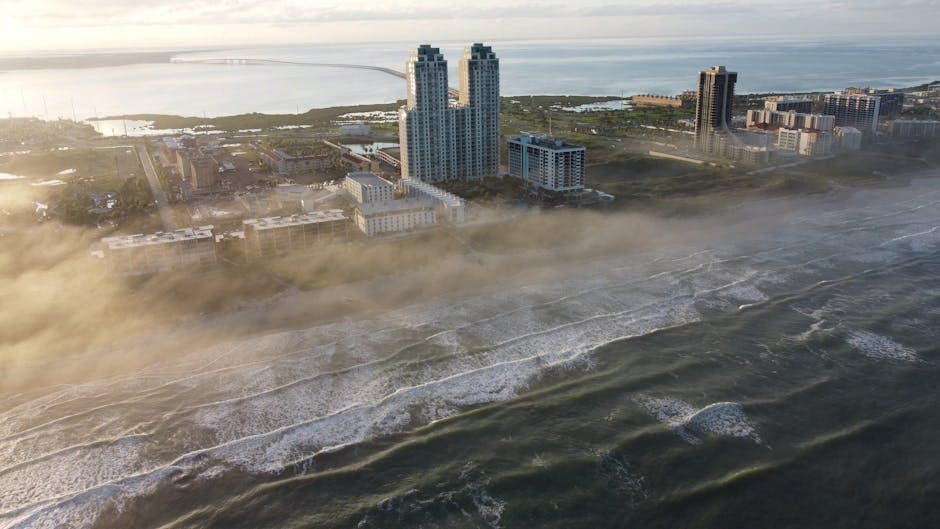 Dramatic aerial view of South Padre Island's foggy coastline with modern architecture and expansive seascape.