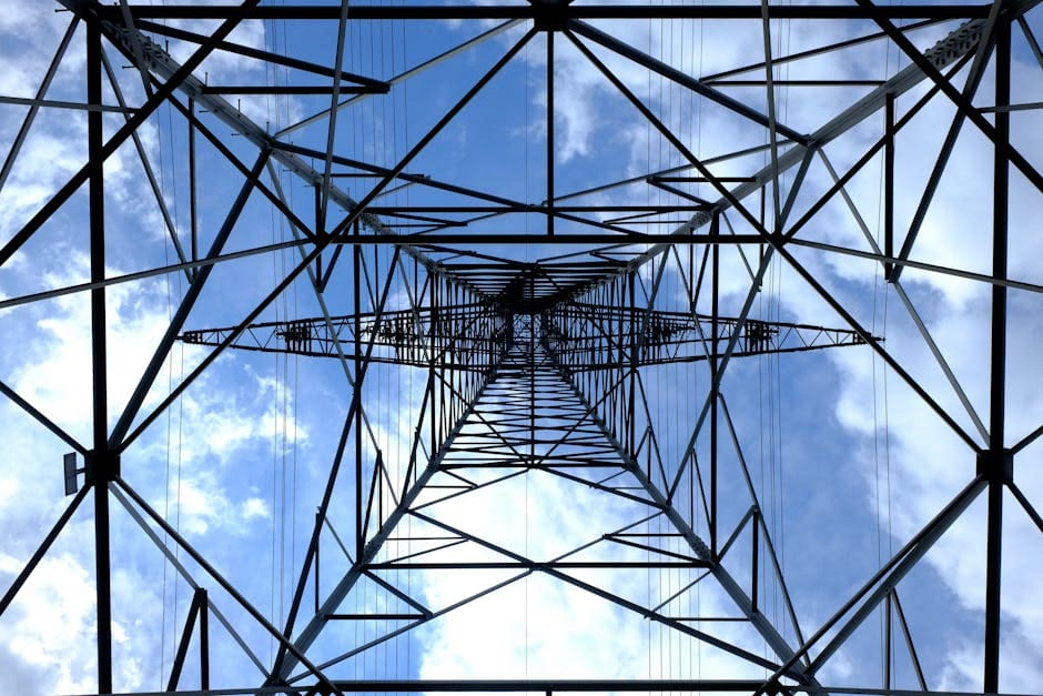 Looking up at a steel power pylon against a bright blue sky.